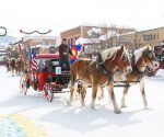 Gambar kereta yang ditarik kuda melewati salju di Karnaval Musim Dingin Steamboat Springs di Colorado